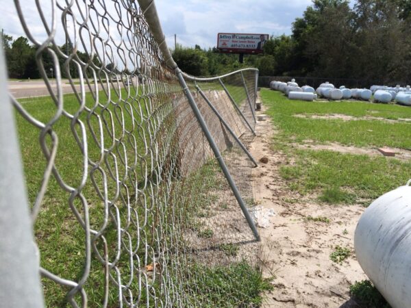 Commercial chain link fence repair in Orlando, FL with leaning fence posts and damaged fence line.