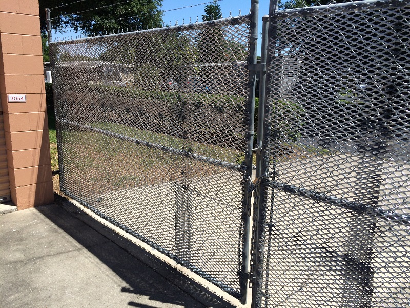Commercial chain link security gate with expanded metal mesh and barbed wire installed in Orlando, FL.