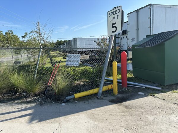 Commercial chain link fence and damaged steel bollard requiring repair after vehicle impact in Orlando, FL.